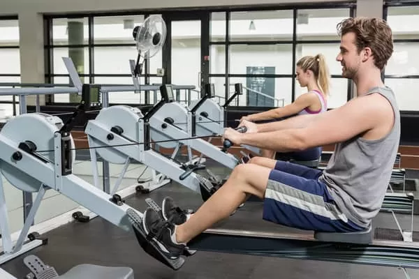 couple at gym doing simple rowing machine workouts