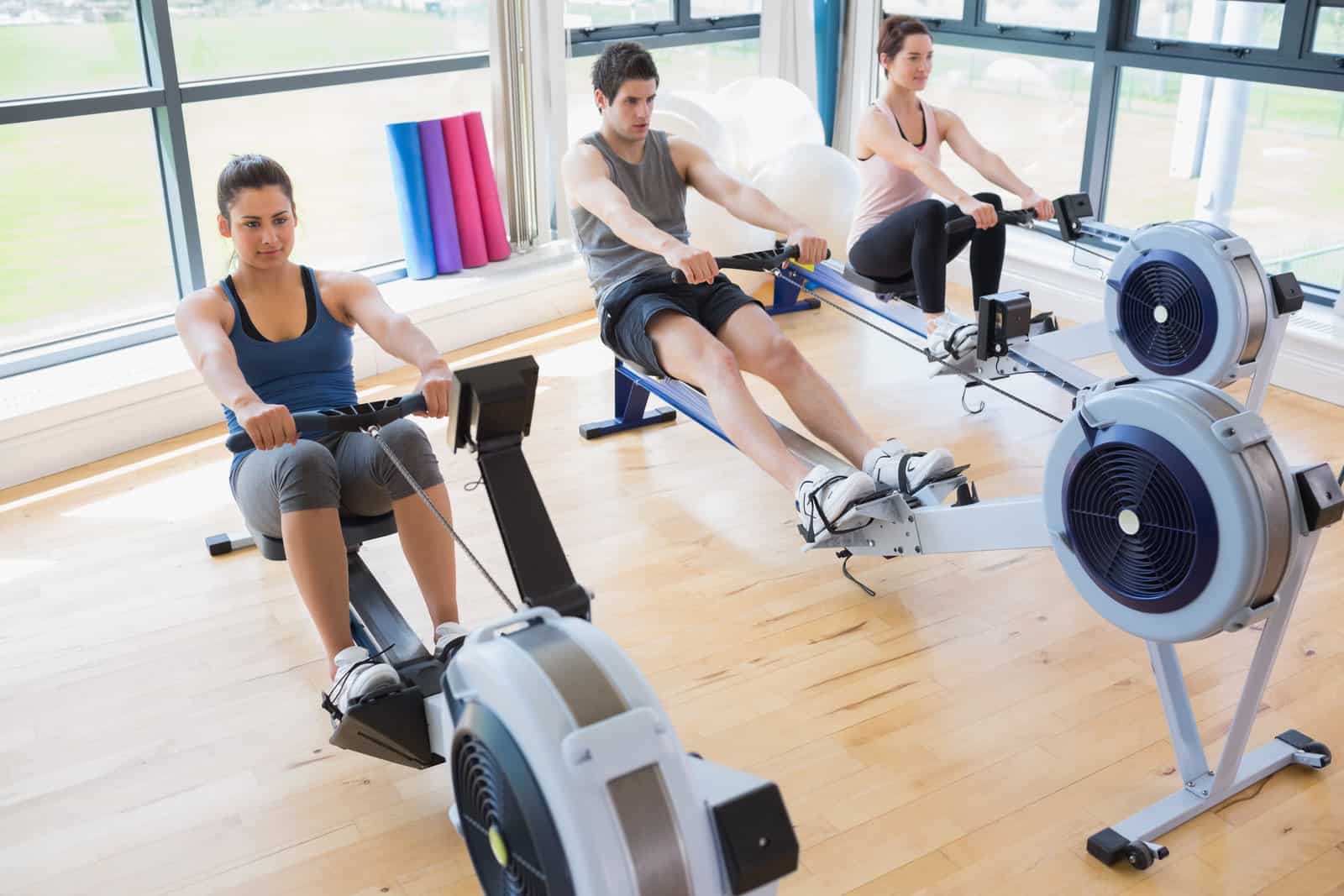 three people using air rowing machines working out together