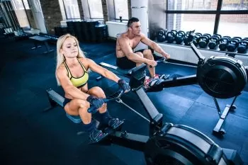 a couple doing a rowing workout at a gym