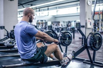 rowing hip pain: man working out correctly on a rowing machine 