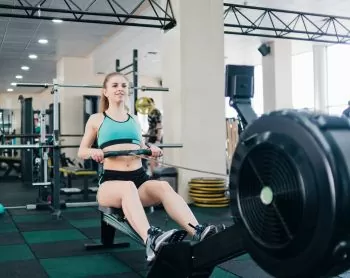 lady working out on a rower in a green t-shirt