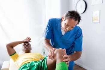 Physician checking injured knees of male athlete