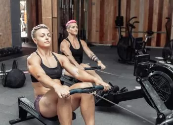 two ladies at the gym rowing to get fit and healthy