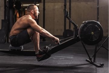 man doing hiit workout on rower at the gym