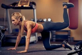 lady lifting back leg up to build her glutes