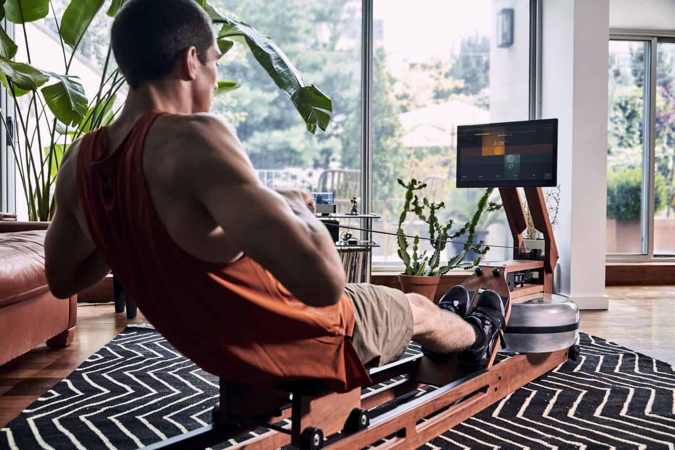 A man rowing on an Ergatta in his living room