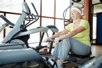 elder woman rowing at the gym