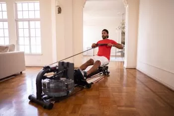 man working out at home on a water rower