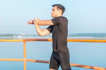 a man stretching his arms and shoulder, a runner warming up and exercising