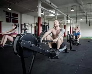 people at gym working out on rowing machines in a group training session