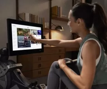 a lady using her rower's touchscreen monitor to choose a workout