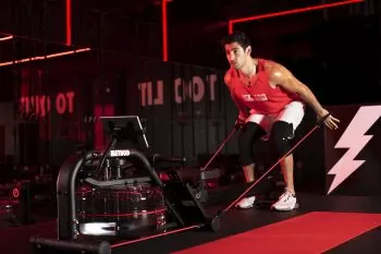 a man in red shirt working out on a LIT Method strength machine using resistance bands