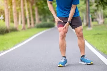 man in wearing a blue shirt holding his painful knee