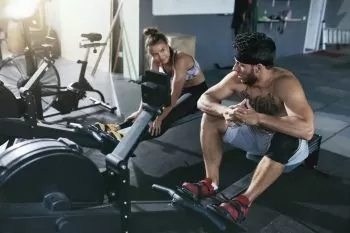 rowing stretches being taught to a lady by trainer
