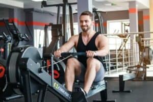 man at gym trying to to lose weight on a rowing machine after exercise bike class 