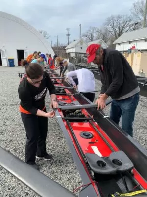 People fixing an 8-Person Crew Boat