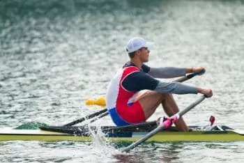 single scull rowing in white cap 
