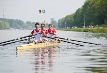 team of men rowing on water in red shirts