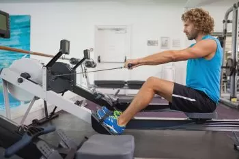 man in blue t-shirt rowing at gym 