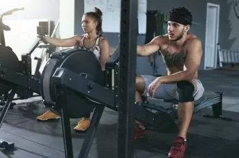 man and lady finishing rowing workout at gym