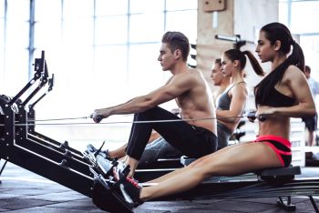 Group of people exercising on rowing machines in a gym