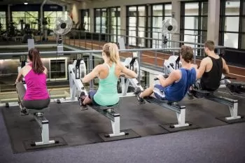 Group of young adults rowing indoors