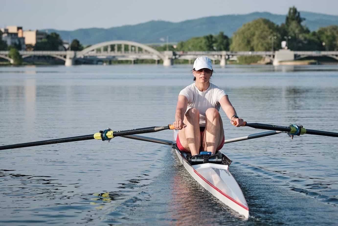 a single sculler rowing on a lake