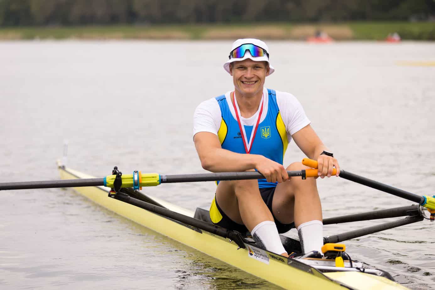 a male Ukrainian rower sculling solo on a lake