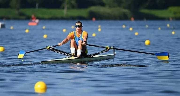 a rower in a single scull with buoys to guide him