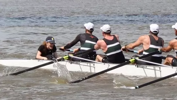 a female coxswain shouting instructions at an all-male rowing team