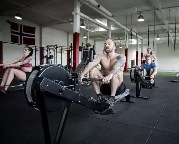 men and women doing indoor rowing workout in a gym