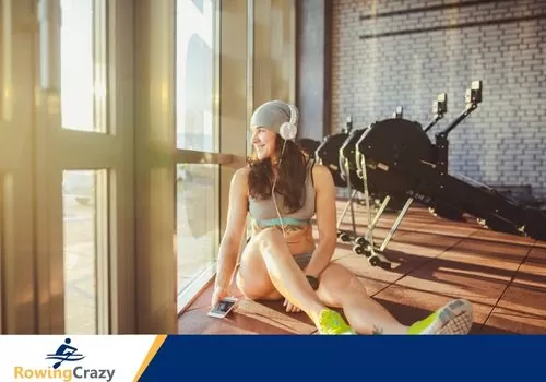 young woman listening to music at a gym with rowing machines